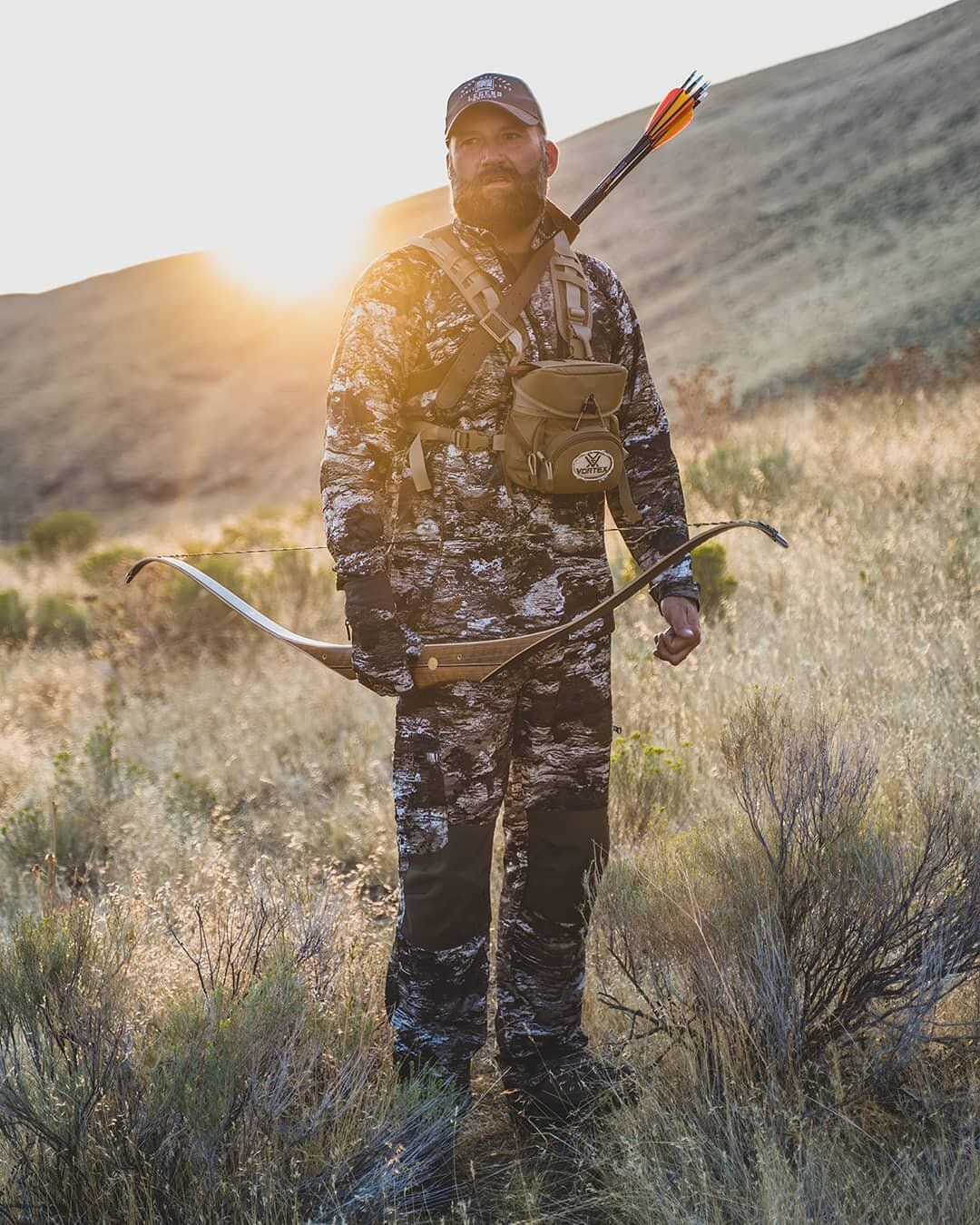 Shane Mowry stands in a field holding a how. 