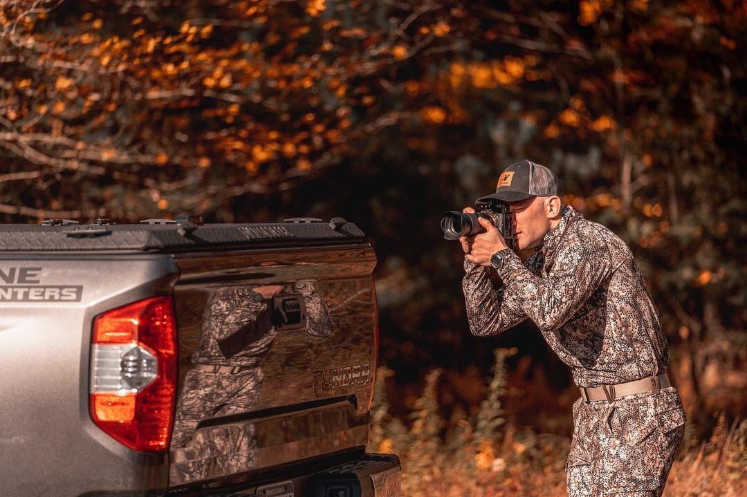 A hunter from Blueline Hunters aims a camera into the distance. 