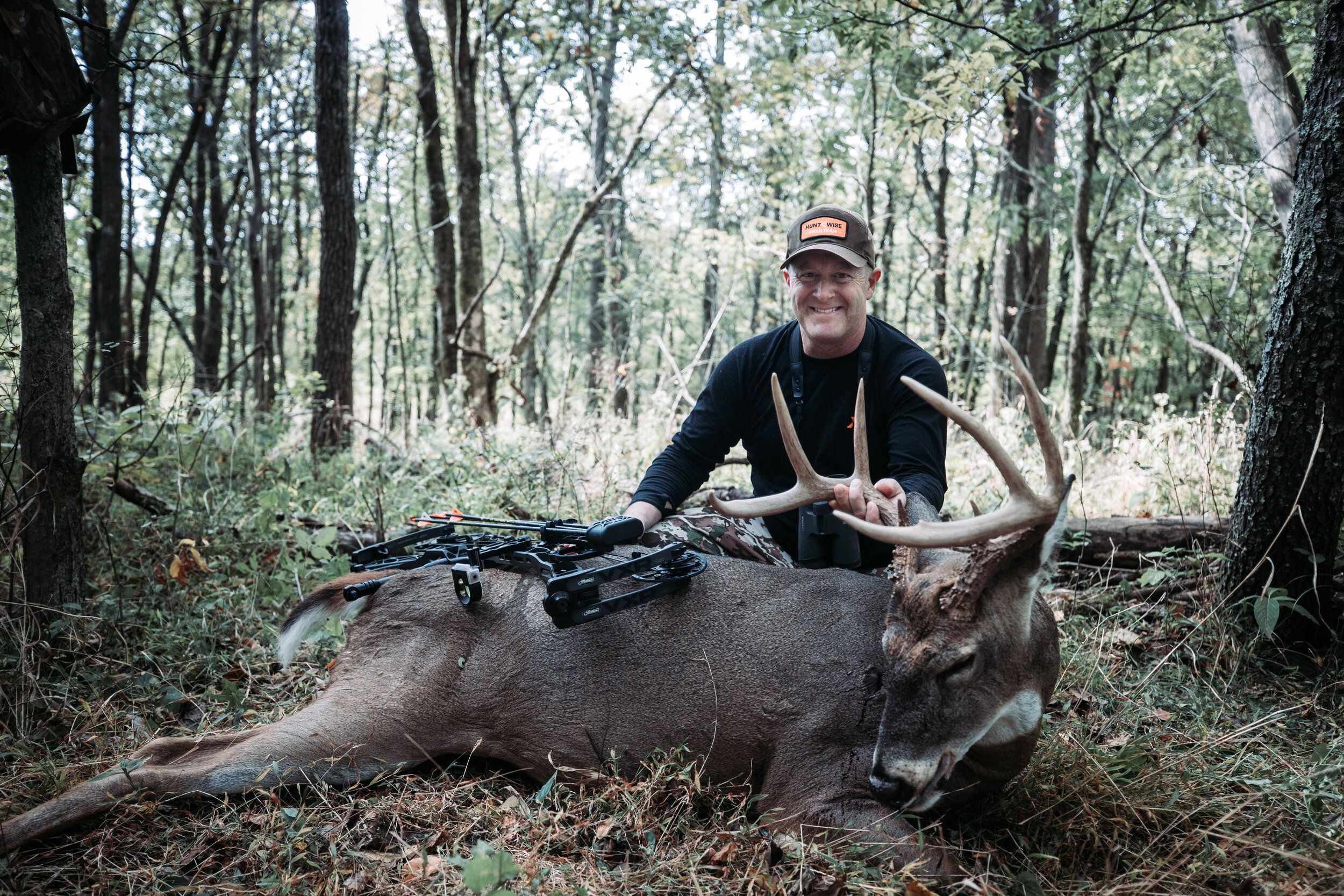 Jeff Sturgis on the ground with a deer kill and his bow. 