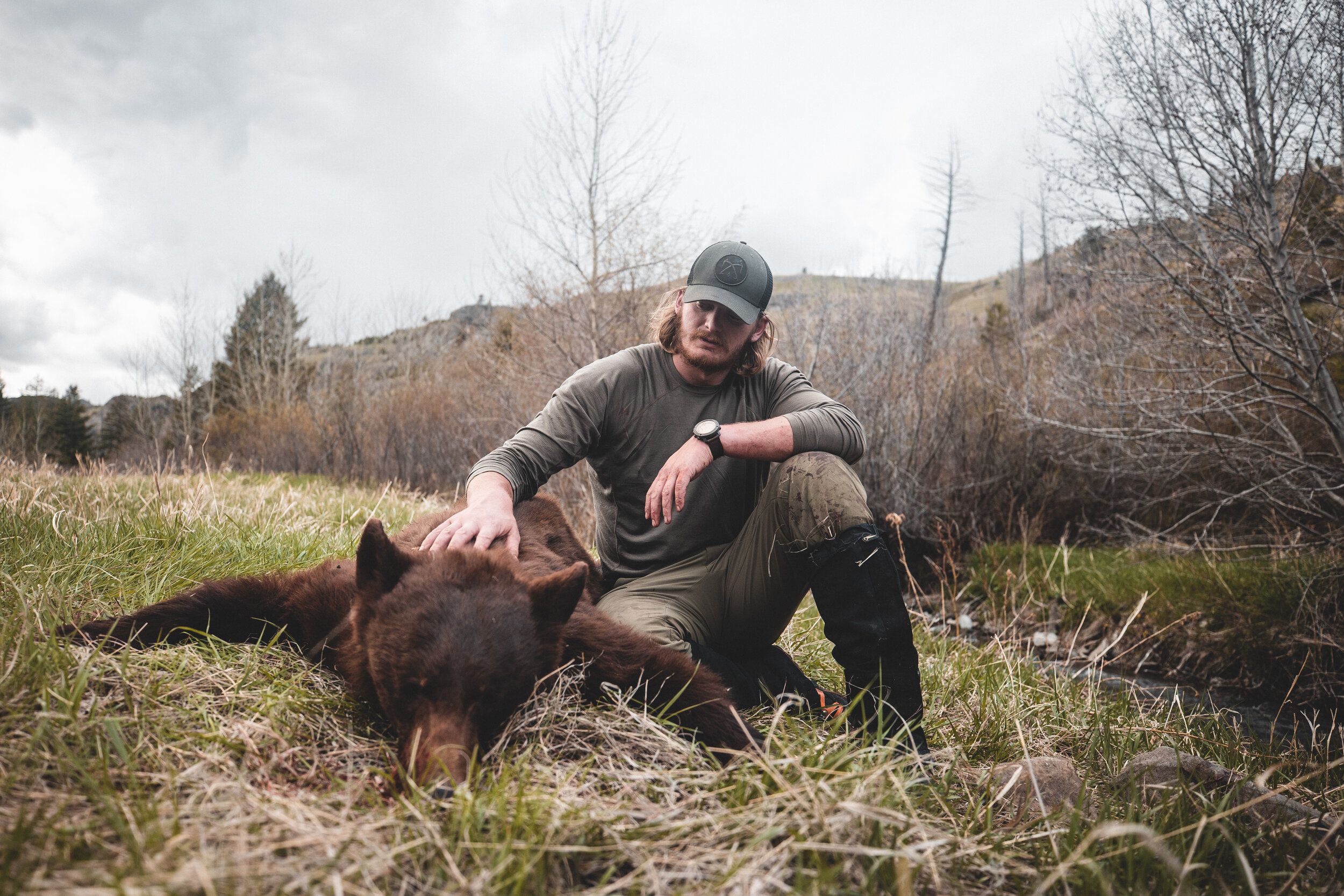 A hunter sits with a bear after the kill, black bear hunting concept. 
