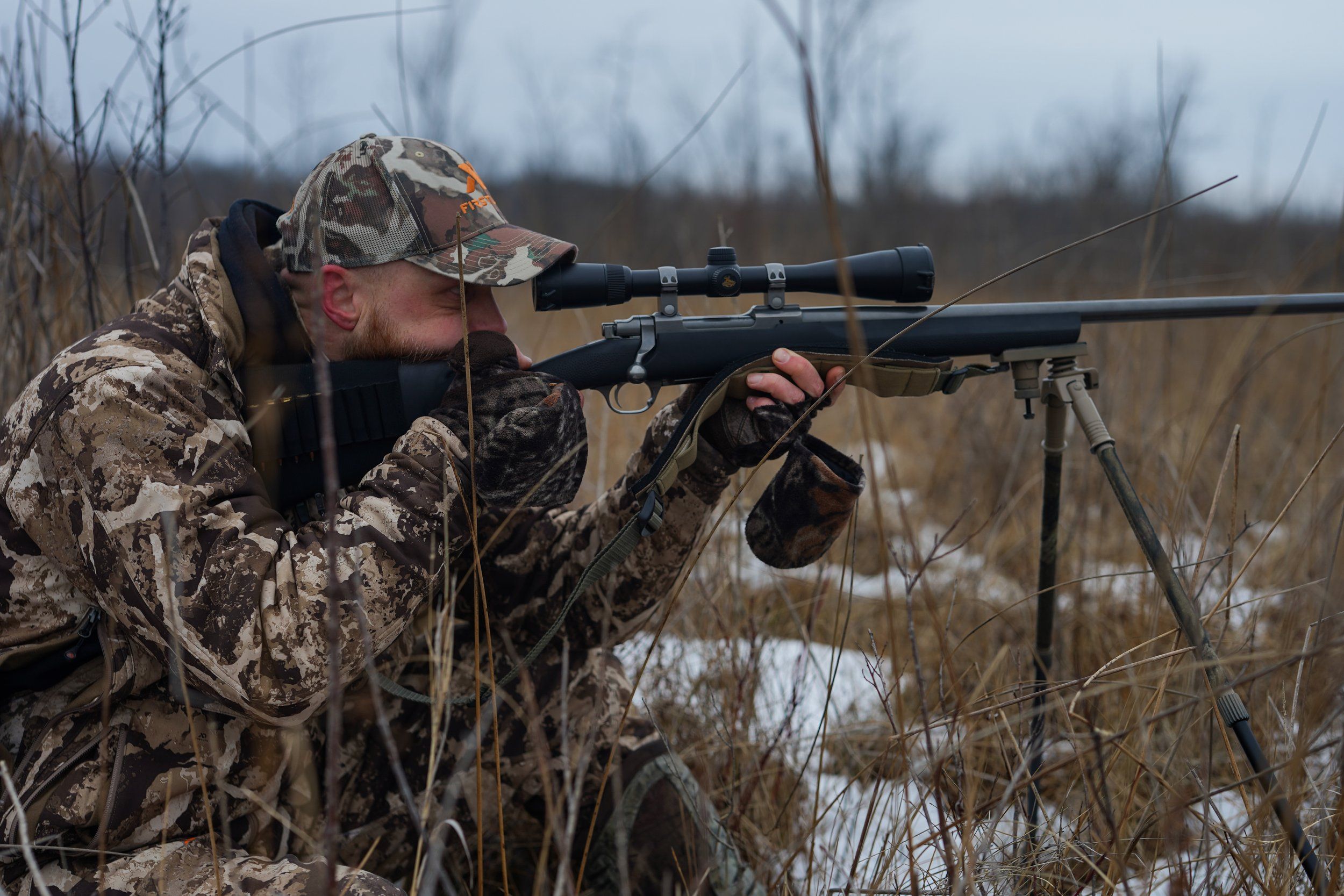 A hunter looking through the scope on a rifle, coyote hunting concept. 