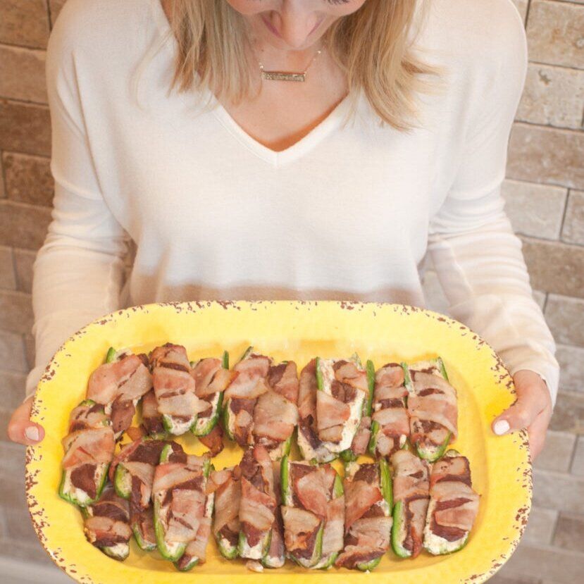 A woman holding a plate of elk poppers, cooking with wild game concept. 