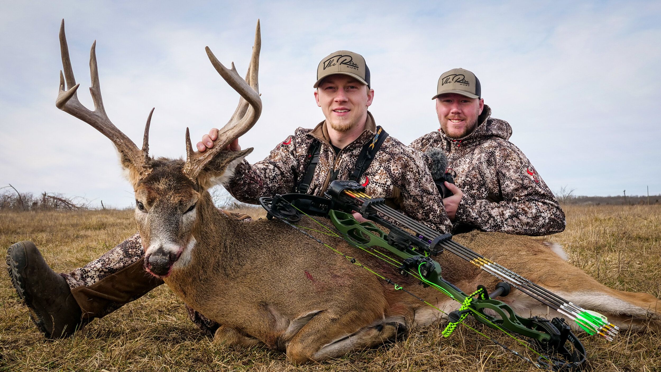 Members of The RISE on the ground with a deer kill and bow. 