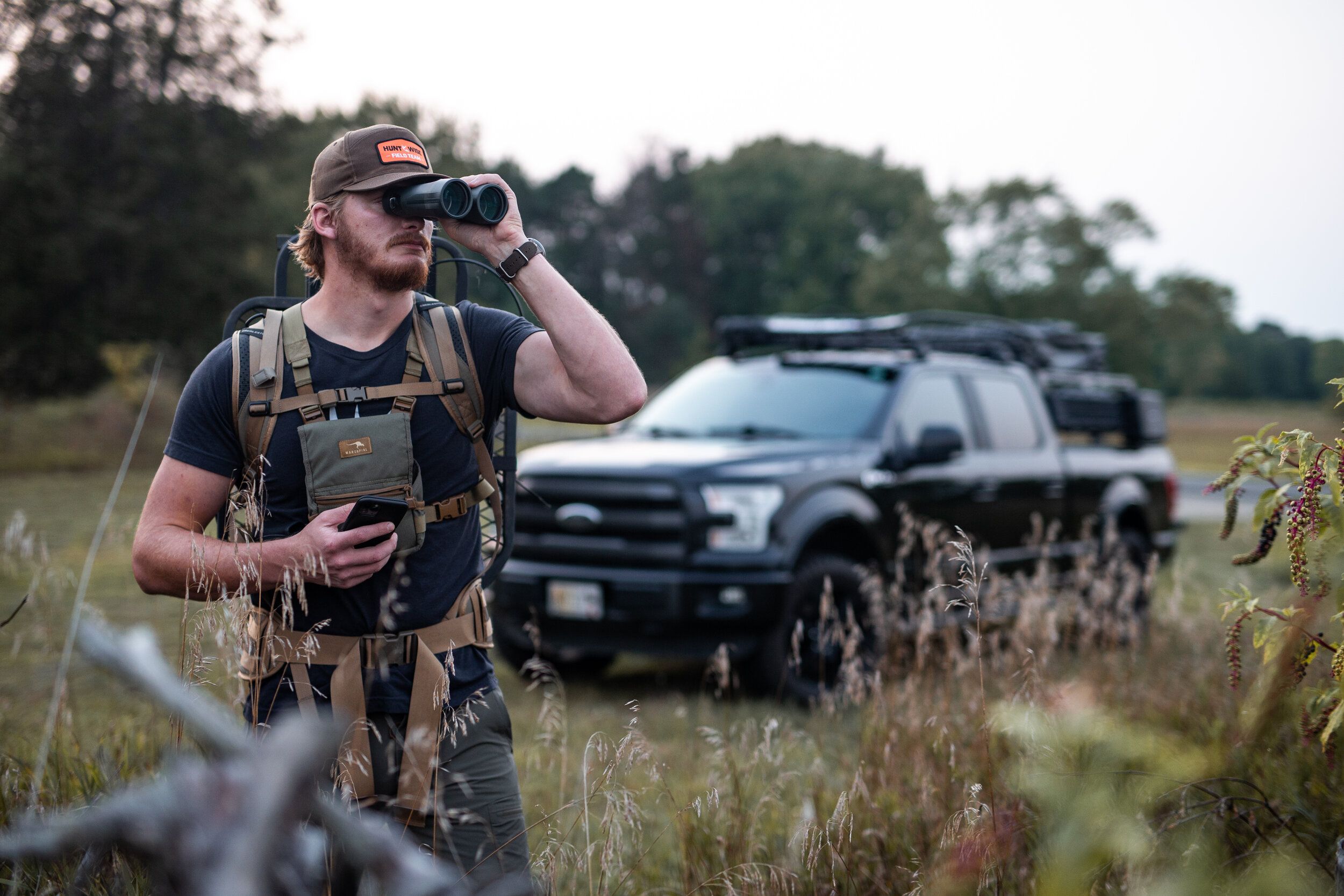 A hunter uses binoculars for scouting public land, whitetail deer hunting concept. 