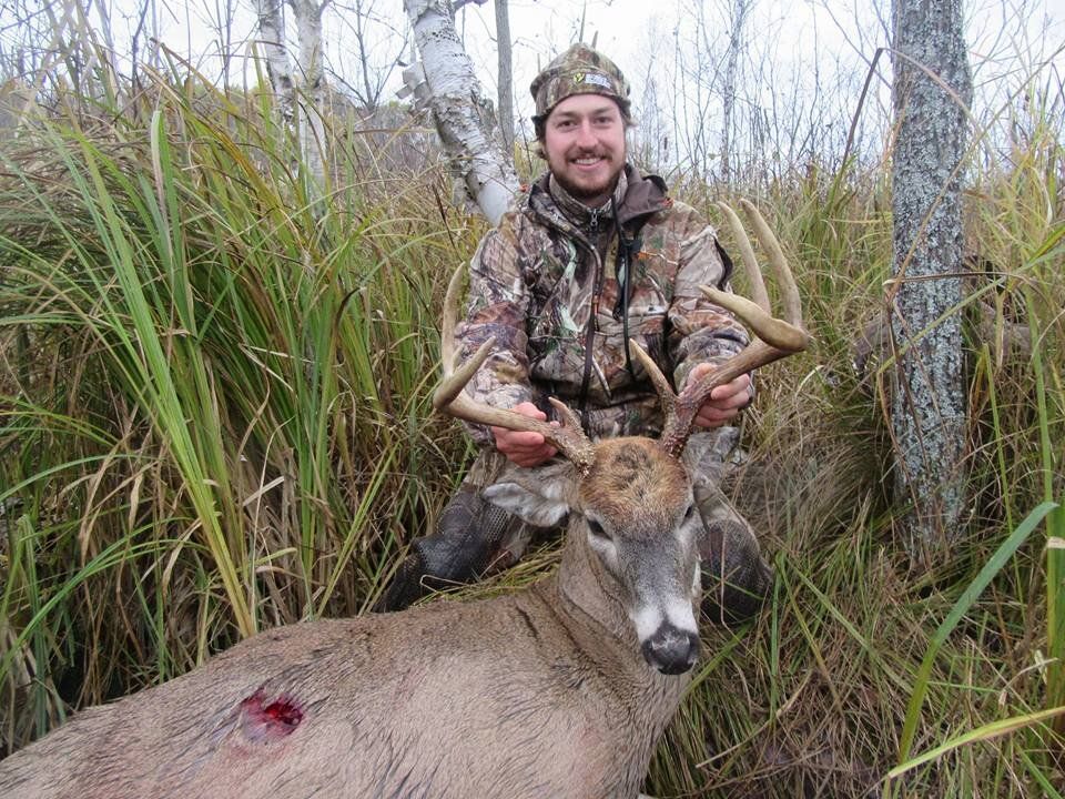 A hunter on the ground holding the head of a deer kill, how to find big bucks on public land concept. 