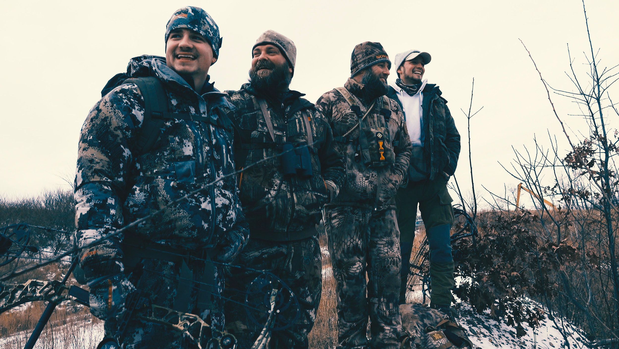 Four members of The Untamed stand together wearing camo for hunting. 